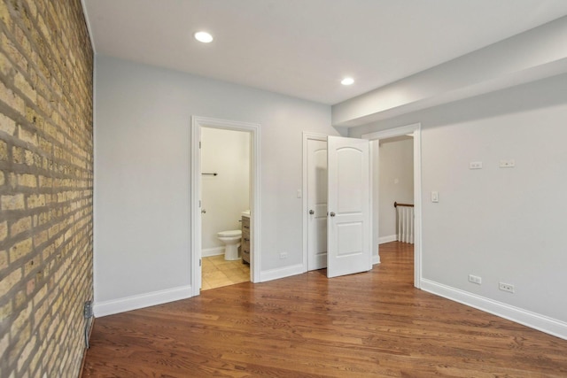 unfurnished bedroom with ensuite bathroom, baseboards, recessed lighting, and wood finished floors