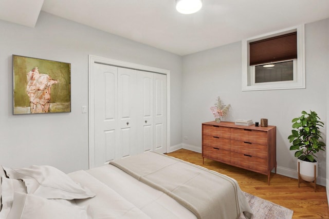 bedroom featuring wood finished floors, baseboards, and a closet