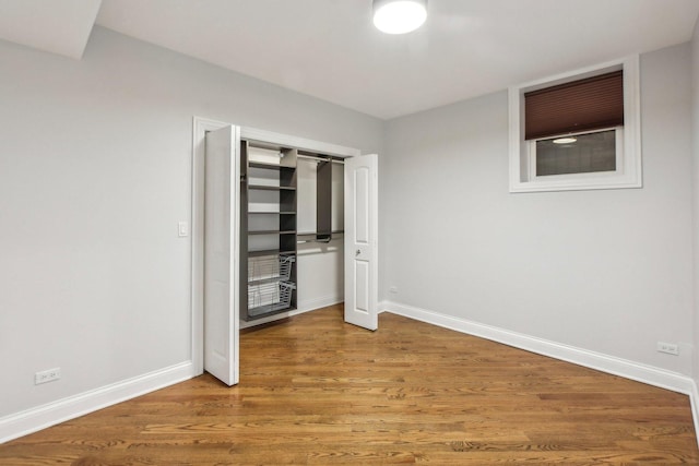 unfurnished bedroom featuring wood finished floors, baseboards, and a closet
