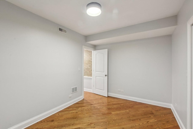 spare room with light wood-style floors, visible vents, and baseboards