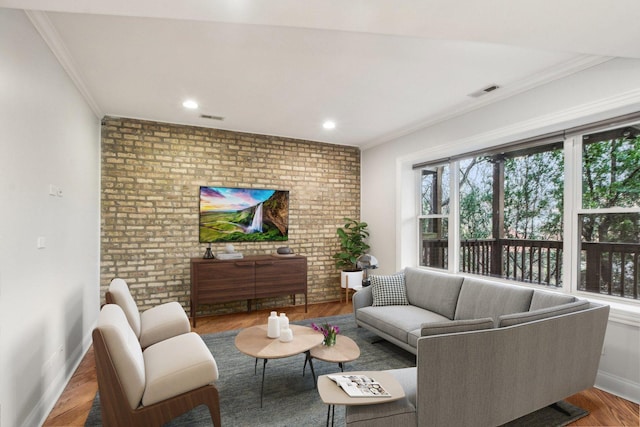 living area with baseboards, ornamental molding, brick wall, visible vents, and wood finished floors
