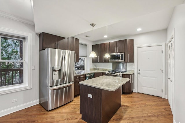 kitchen featuring hanging light fixtures, dark brown cabinetry, light stone countertops, a kitchen island, and stainless steel appliances
