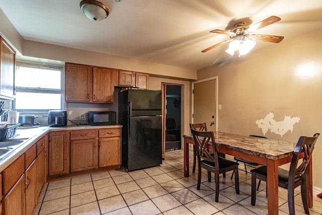 kitchen featuring light tile patterned floors, ceiling fan, light countertops, brown cabinets, and black appliances