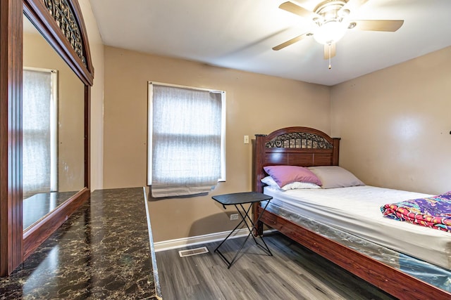 bedroom featuring wood finished floors, baseboards, a ceiling fan, and visible vents