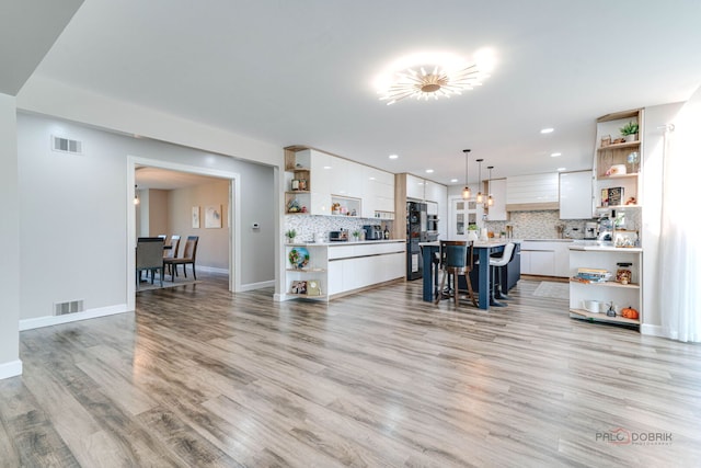 living area with baseboards, visible vents, light wood finished floors, and recessed lighting