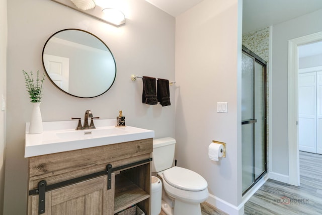 bathroom featuring a shower stall, baseboards, toilet, wood finished floors, and vanity