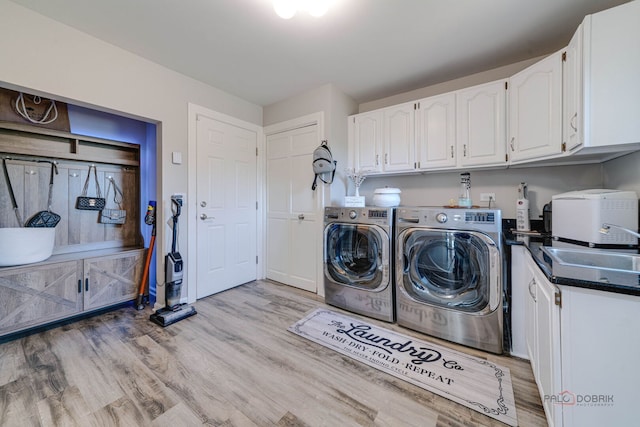 washroom with a sink, light wood-type flooring, cabinet space, and washing machine and dryer