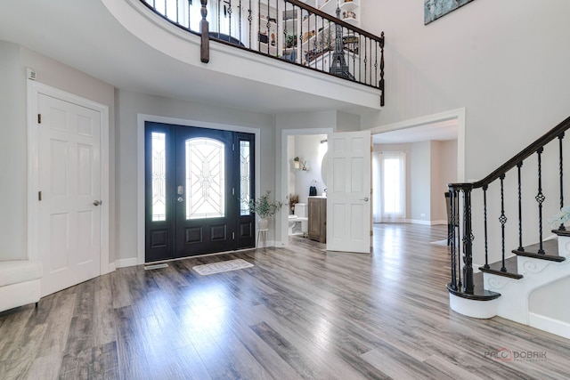 entrance foyer with a high ceiling, stairway, wood finished floors, and baseboards