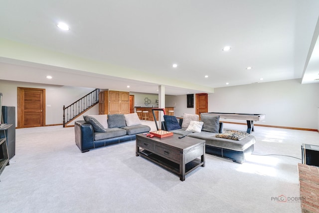 living room with recessed lighting, light colored carpet, bar, baseboards, and stairway