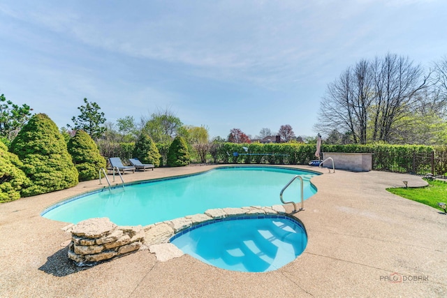 view of pool featuring a patio, a pool with connected hot tub, and fence
