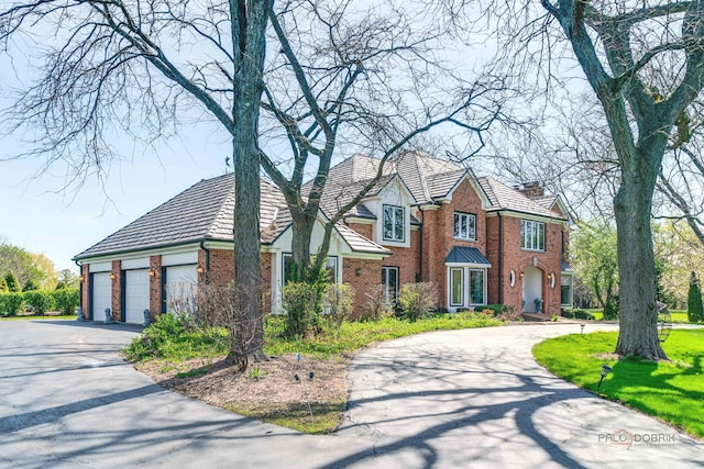 view of front of home featuring driveway, a garage, and brick siding