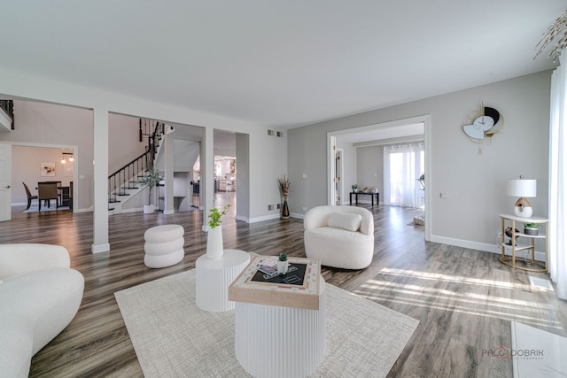living area with visible vents, wood finished floors, and stairs