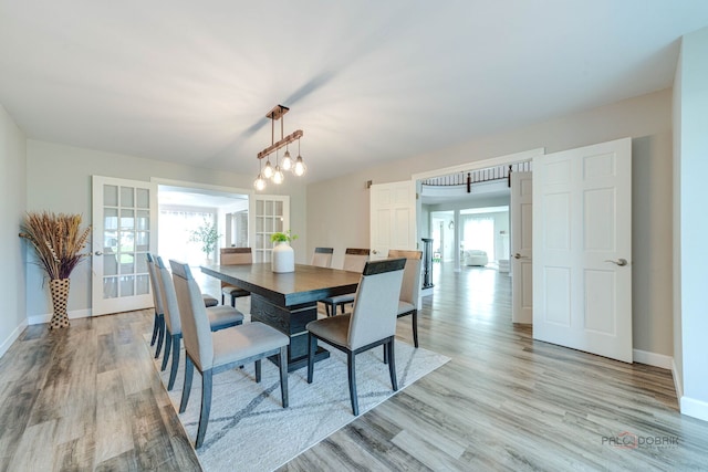 dining space with light wood finished floors, french doors, and baseboards
