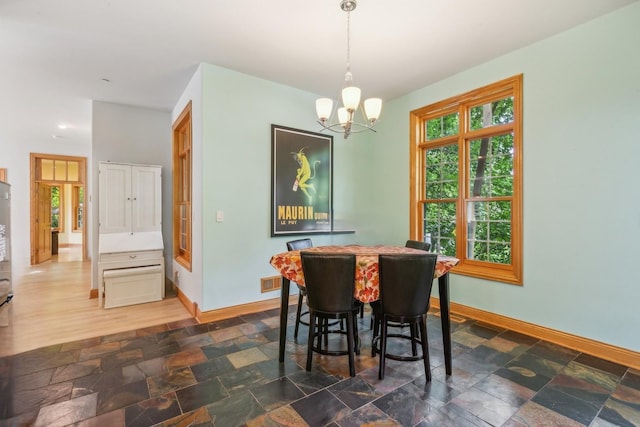 dining space featuring visible vents, baseboards, a chandelier, and stone finish flooring