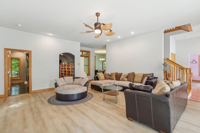 living area with baseboards, light wood-type flooring, recessed lighting, stairway, and ceiling fan with notable chandelier