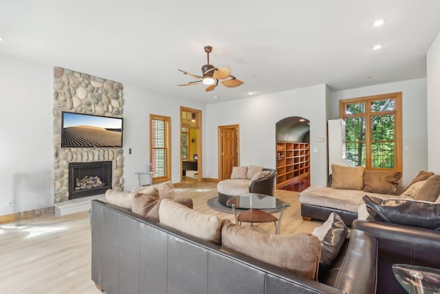 living area featuring baseboards, a stone fireplace, recessed lighting, light wood-style flooring, and a ceiling fan