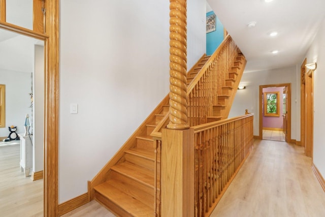 staircase featuring wood finished floors, baseboards, and recessed lighting