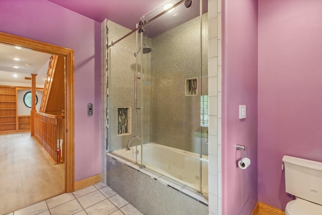 bathroom featuring tiled shower / bath combo, toilet, baseboards, and tile patterned floors