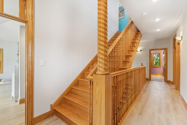 stairway featuring wood finished floors, baseboards, and recessed lighting