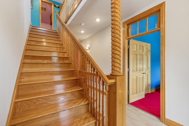 stairway featuring wood finished floors and visible vents