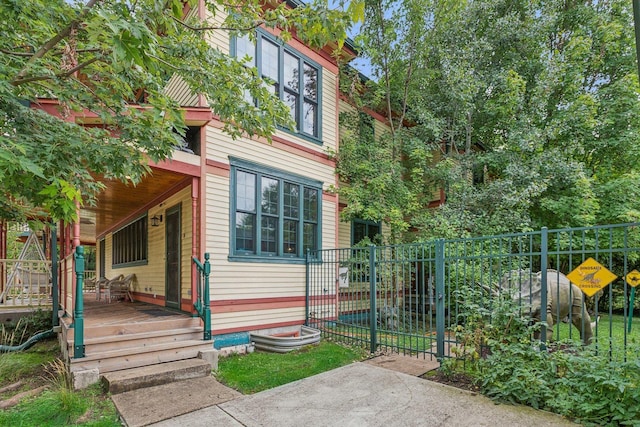 view of side of property featuring a porch and fence