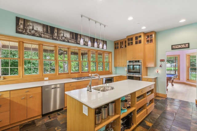 kitchen featuring track lighting, a sink, stone tile flooring, light countertops, and appliances with stainless steel finishes