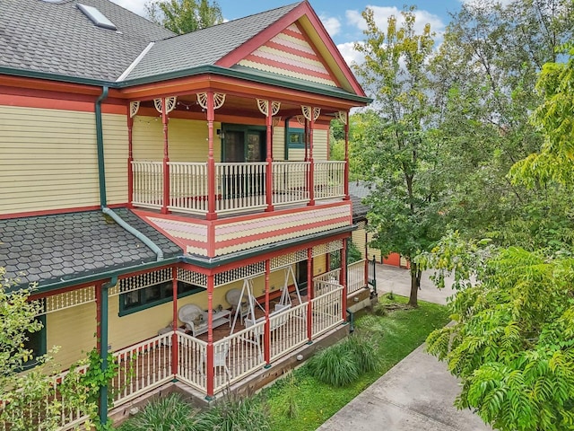rear view of property featuring a porch and a shingled roof