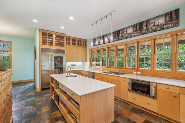 kitchen featuring light countertops, appliances with stainless steel finishes, a sink, and stone finish flooring
