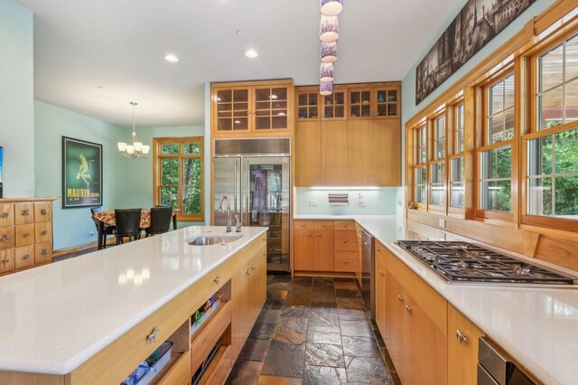 kitchen with an inviting chandelier, a wealth of natural light, appliances with stainless steel finishes, light countertops, and stone tile flooring
