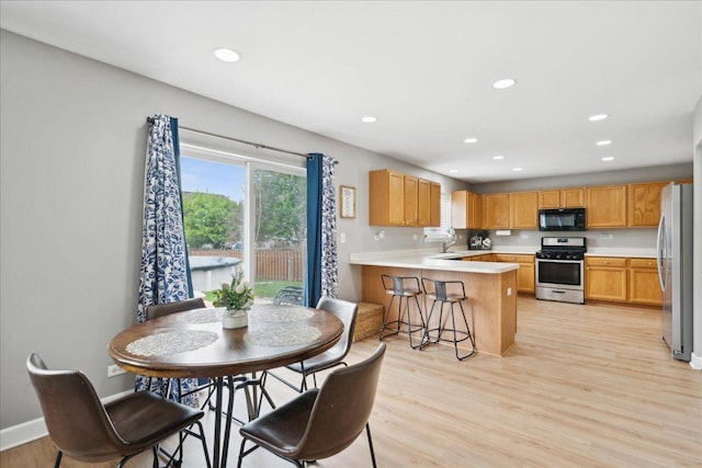 kitchen with a peninsula, appliances with stainless steel finishes, recessed lighting, and light wood-style floors