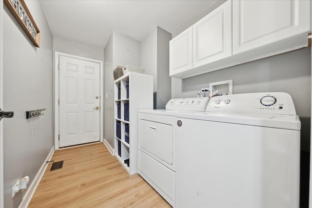 clothes washing area with visible vents, cabinet space, baseboards, light wood-style floors, and washer and dryer