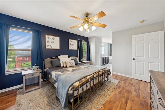 bedroom featuring baseboards, a ceiling fan, ensuite bathroom, and wood finished floors