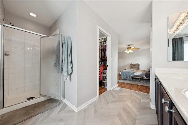 bathroom with double vanity, a ceiling fan, a shower stall, baseboards, and recessed lighting