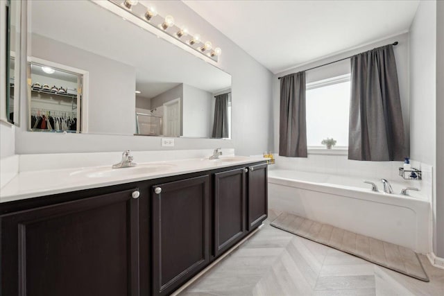 full bath with double vanity, a sink, a garden tub, and a stall shower