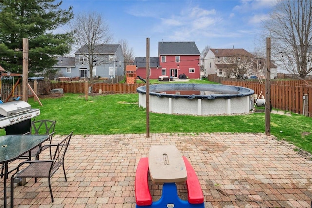 view of patio / terrace with grilling area, outdoor dining area, a fenced backyard, a playground, and a residential view