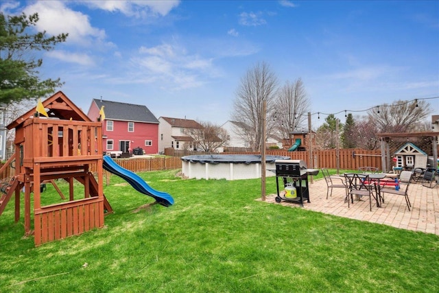 view of yard featuring a patio, a fenced in pool, a fenced backyard, and a playground