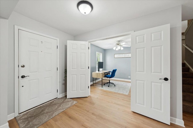 entryway featuring light wood-style floors, a ceiling fan, stairs, and baseboards