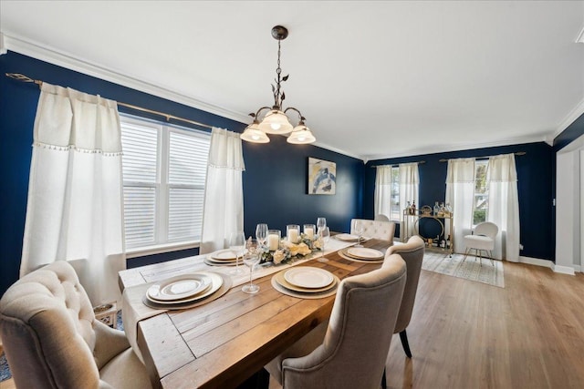 dining space featuring light wood-style floors, ornamental molding, and baseboards