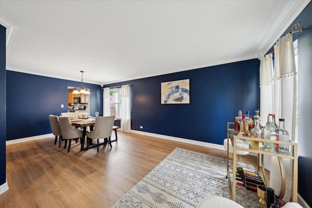 dining area featuring an inviting chandelier, ornamental molding, baseboards, and wood finished floors