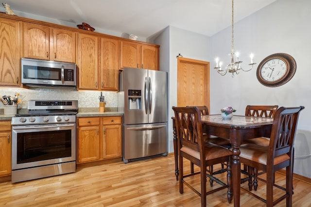 kitchen featuring light wood-style flooring, brown cabinetry, a chandelier, and stainless steel appliances