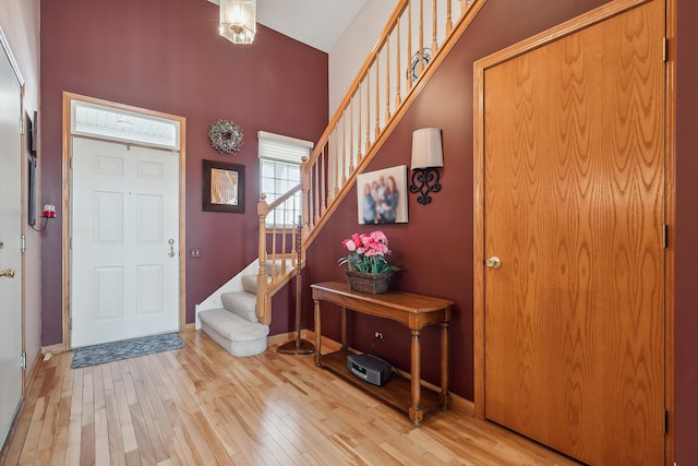 entrance foyer featuring high vaulted ceiling, stairway, light wood-style flooring, and baseboards