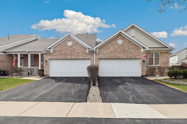view of front of property with driveway, a garage, covered porch, and brick siding