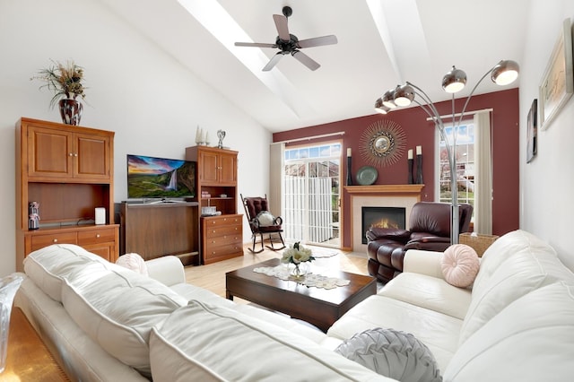 living room featuring a lit fireplace, ceiling fan, lofted ceiling with beams, and a wealth of natural light