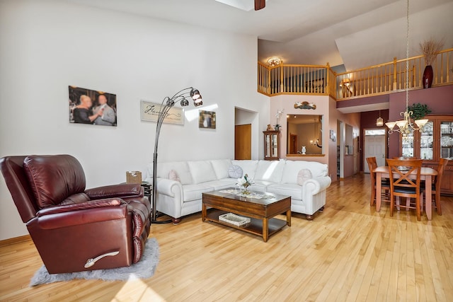 living area featuring a towering ceiling, hardwood / wood-style flooring, and ceiling fan with notable chandelier