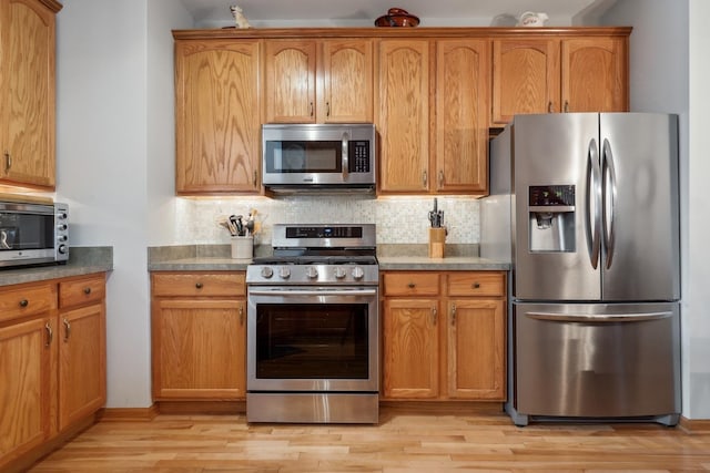 kitchen with stainless steel appliances, tasteful backsplash, and light wood-type flooring