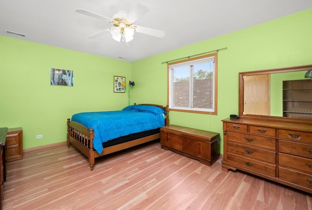 bedroom with light wood-style floors, a ceiling fan, and baseboards