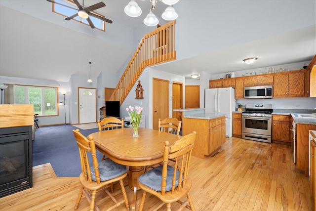 dining area with high vaulted ceiling, stairway, ceiling fan, and light wood-type flooring