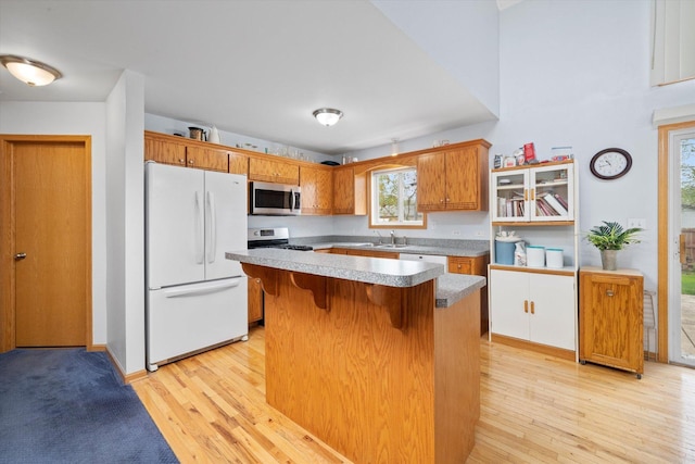 kitchen with stainless steel appliances, a kitchen bar, light wood-style floors, and brown cabinets
