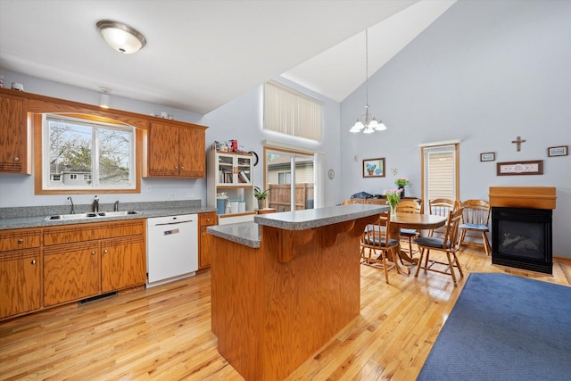 kitchen featuring dishwasher, a sink, light wood-type flooring, high vaulted ceiling, and a center island