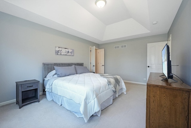 bedroom featuring a tray ceiling, light carpet, baseboards, and visible vents